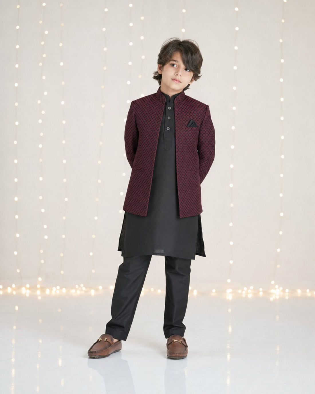Boy wearing maroon embossed diamond pattern Prince Coat with black kurta trouser — full front view