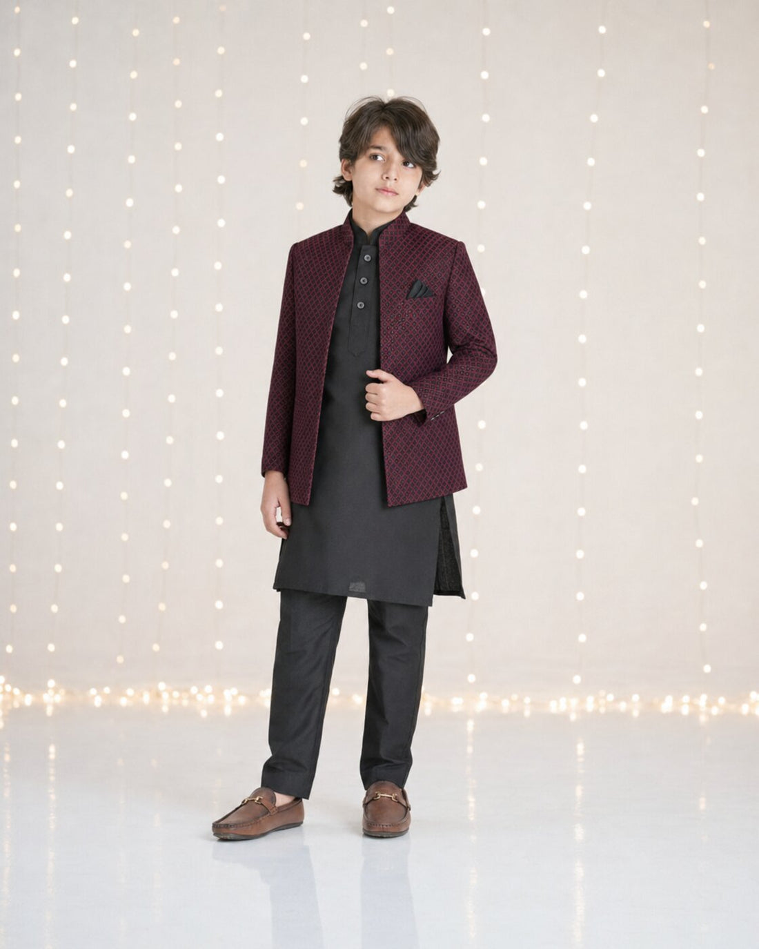 Boy wearing maroon embossed diamond pattern Prince Coat with black kurta trouser — full front view